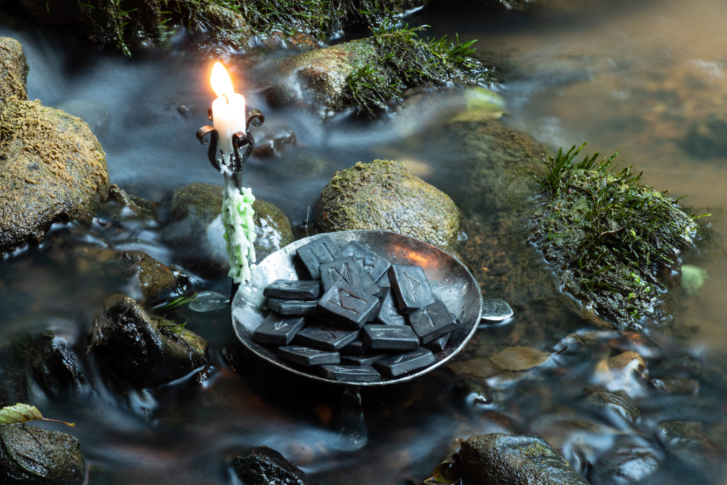 Norse Runes in a forged bowl with candle. In the evening  on the river